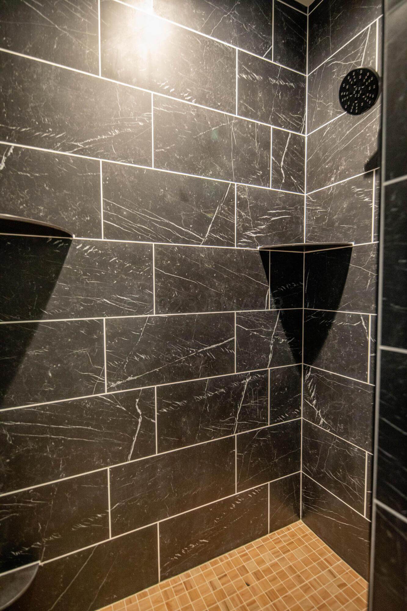 a shower with a black tile wall.
