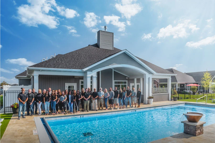 A Group Of People Standing In Front Of A Pool